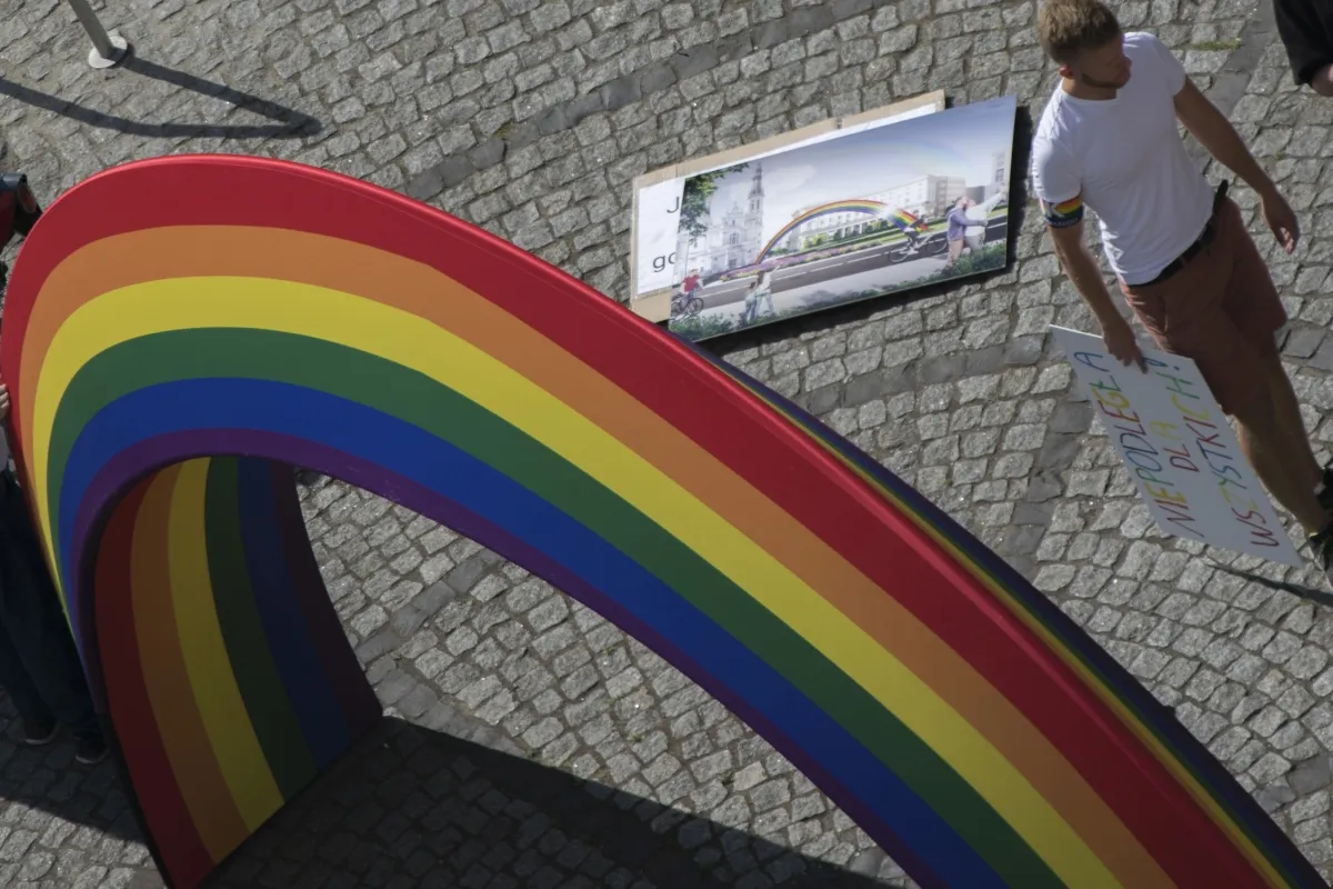 Top curve of a rainbow arch seen from above beside a protest sign